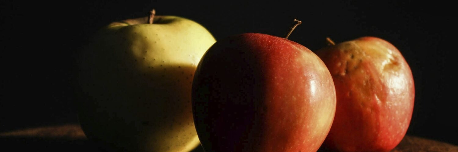 three apples sitting on top of a wooden table