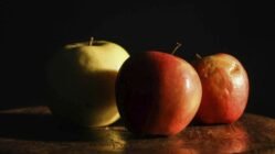 three apples sitting on top of a wooden table