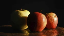 three apples sitting on top of a wooden table